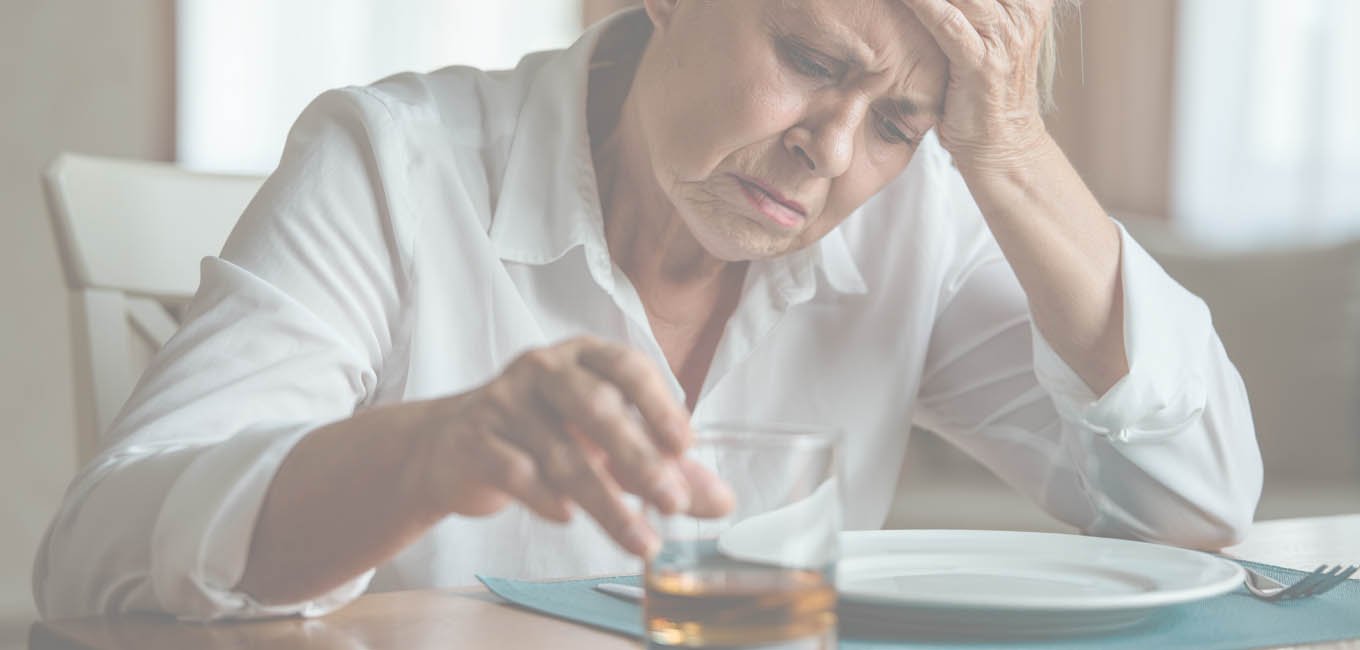 Женщина сидит за столом со стаканом виски